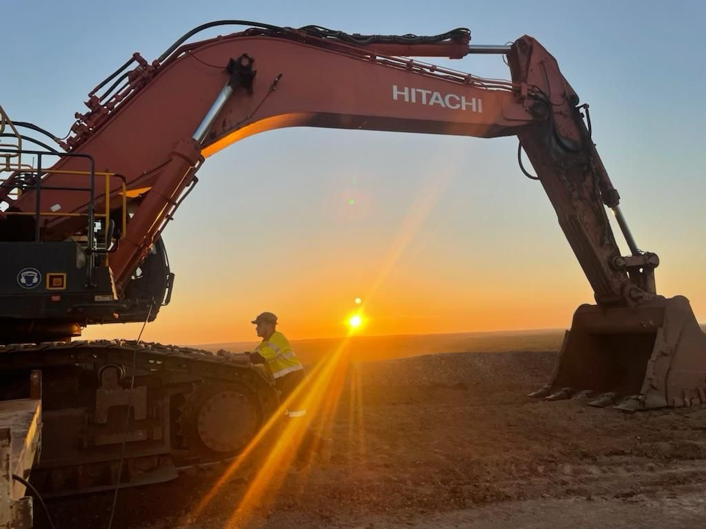 Hitachi excavator at sunset with worker